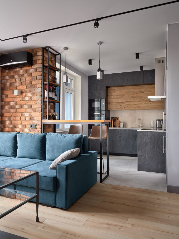 На фото: гостиная комната среднего размера в стиле лофт с коричневыми стенами, полом из ламината, зоной отдыха, коричневым полом, кирпичными стенами и синим диваном с