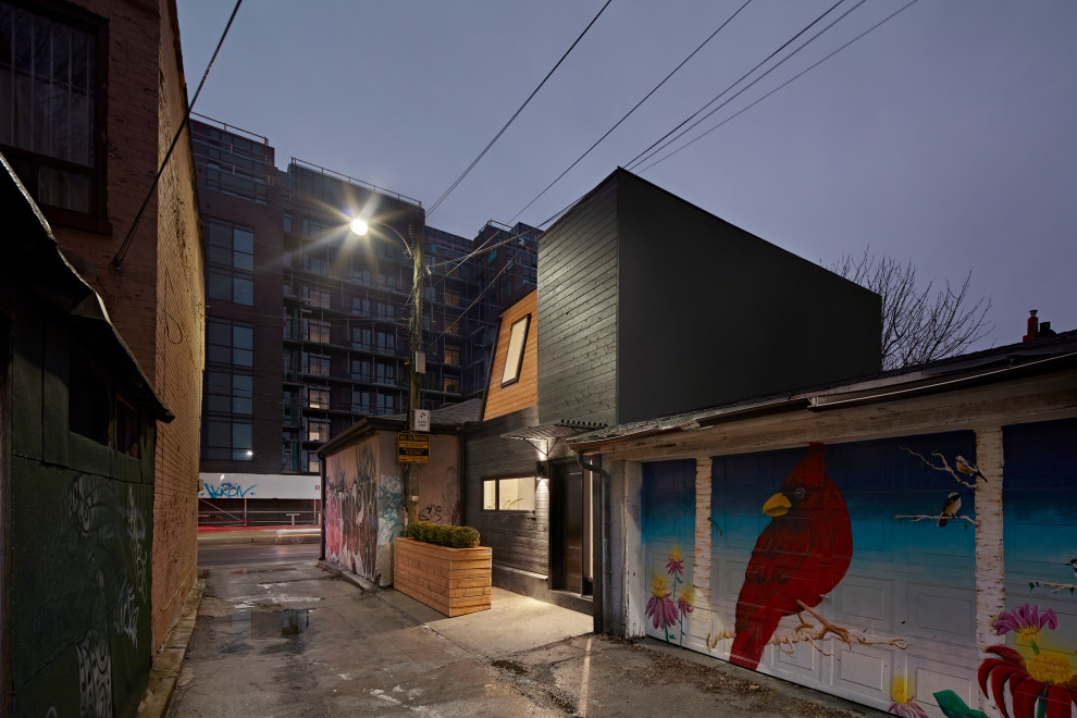 Aménagement d'une façade de Tiny House noire scandinave en bois et bardeaux à un étage avec un toit plat.