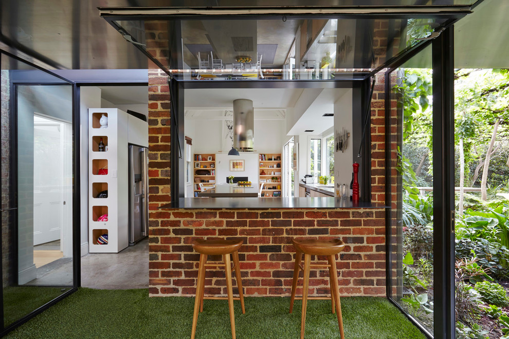 This is an example of a mid-sized contemporary eat-in kitchen in Melbourne with flat-panel cabinets, white cabinets, concrete floors and with island.