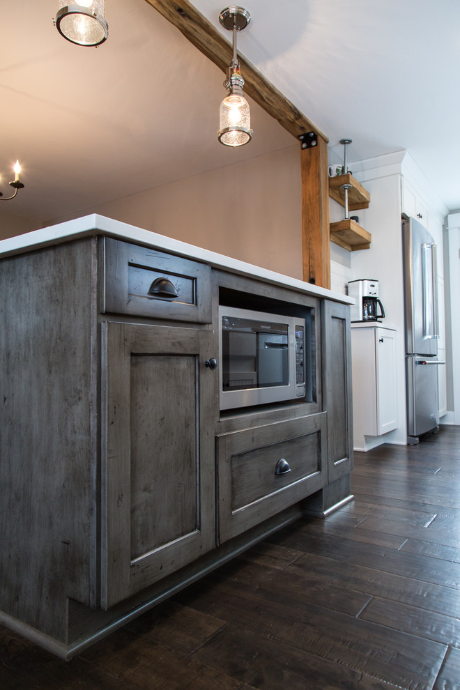Photo of a small country galley eat-in kitchen in Portland with a farmhouse sink, shaker cabinets, white cabinets, quartz benchtops, white splashback, subway tile splashback, stainless steel appliances, dark hardwood floors and with island.