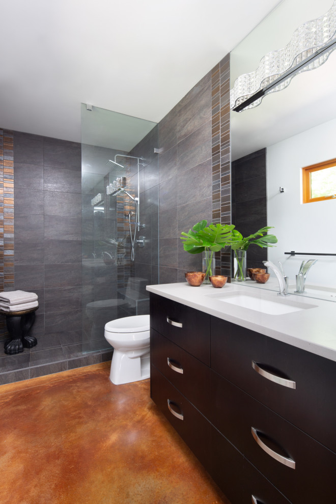 This is an example of a mid-sized transitional master bathroom in Vancouver with flat-panel cabinets, dark wood cabinets, a curbless shower, a one-piece toilet, gray tile, porcelain tile, white walls, concrete floors, engineered quartz benchtops, orange floor, an open shower, grey benchtops and a built-in vanity.