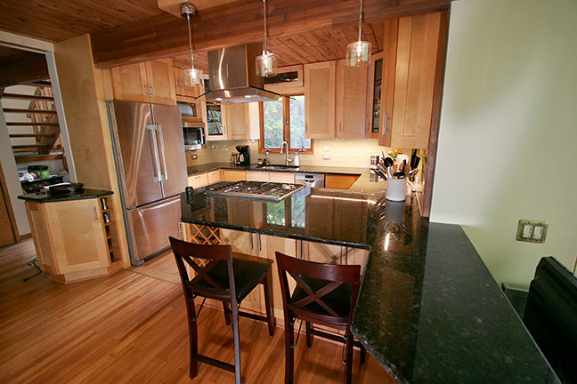 Inspiration for a small transitional l-shaped porcelain tile eat-in kitchen remodel with shaker cabinets, light wood cabinets, granite countertops, beige backsplash, glass tile backsplash, stainless steel appliances and a peninsula
