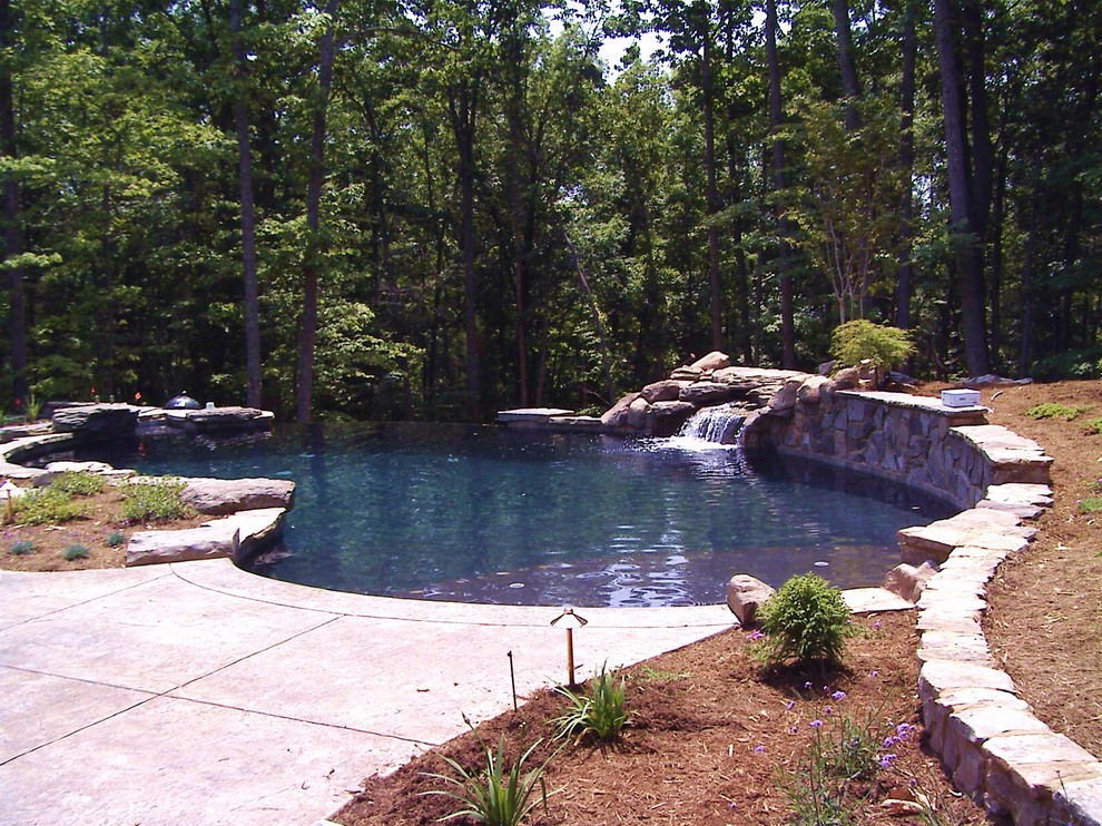 Design ideas for a mid-sized traditional custom-shaped infinity pool in Raleigh with stamped concrete.