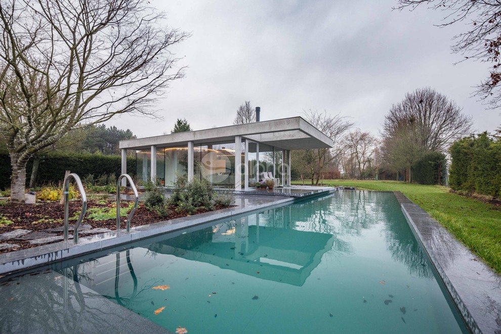 This is an example of a large contemporary backyard rectangular lap pool in Seattle with a pool house and natural stone pavers.