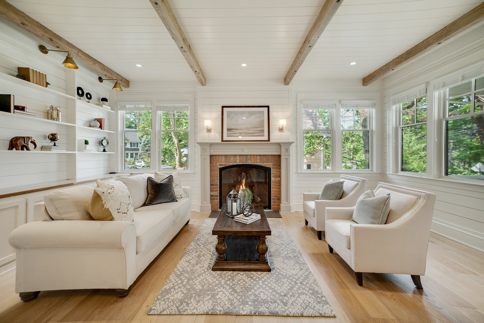Country formal enclosed living room in Philadelphia with white walls, light hardwood floors, a standard fireplace, a brick fireplace surround and beige floor.