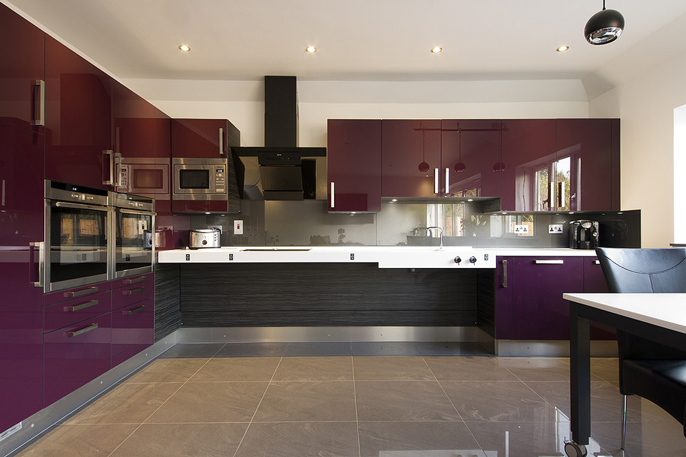 Photo of a mid-sized contemporary l-shaped open plan kitchen in Essex with an integrated sink, flat-panel cabinets, purple cabinets, solid surface benchtops, metallic splashback, glass sheet splashback, stainless steel appliances, porcelain floors and grey floor.