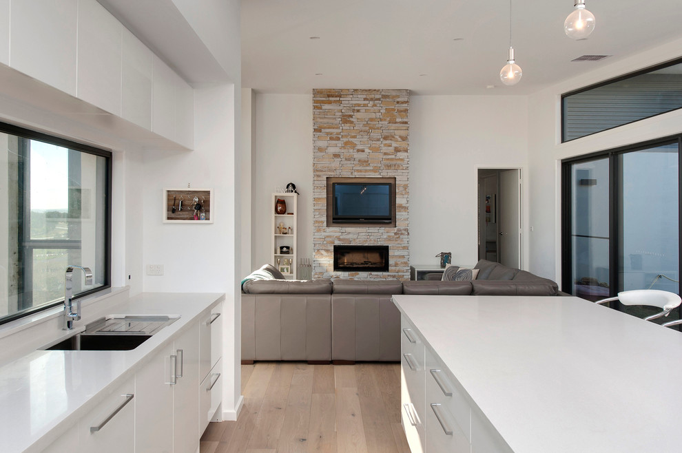 Inspiration for a large contemporary open concept living room in Canberra - Queanbeyan with white walls, light hardwood floors, a standard fireplace, a stone fireplace surround and a wall-mounted tv.