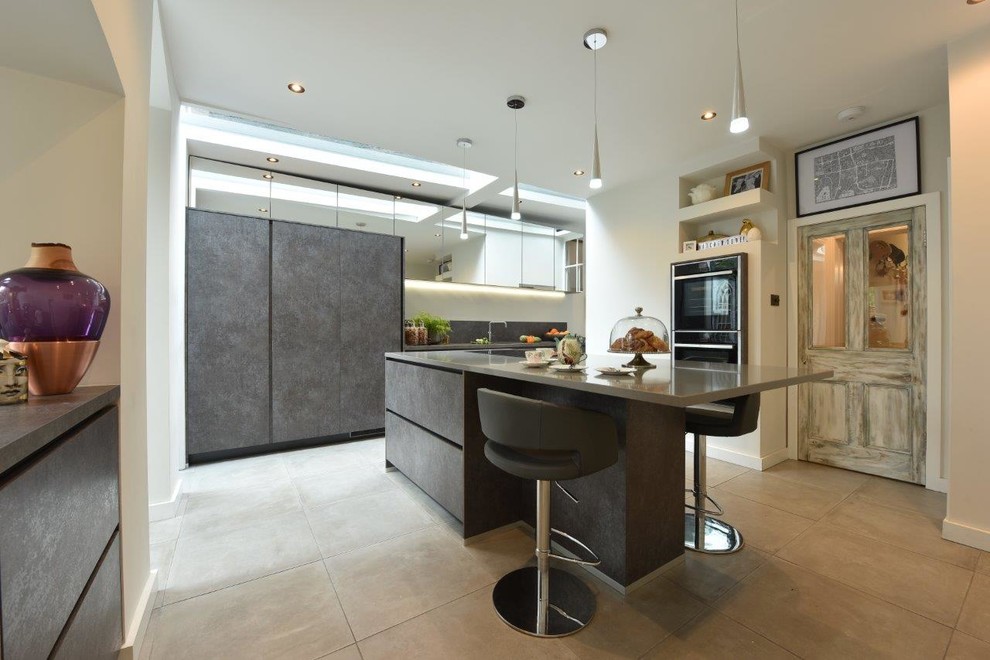 This is an example of a mid-sized contemporary galley eat-in kitchen in Manchester with an undermount sink, flat-panel cabinets, grey cabinets, solid surface benchtops, grey splashback, porcelain floors, with island and grey floor.