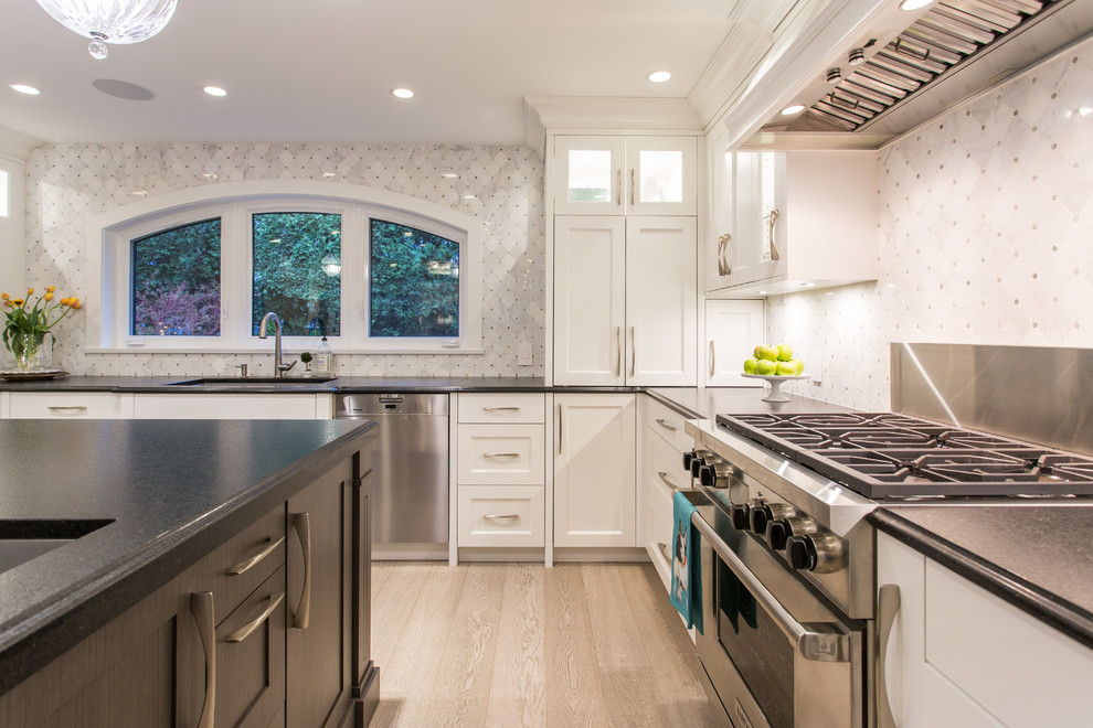 Eat-in kitchen - large transitional l-shaped medium tone wood floor and beige floor eat-in kitchen idea in Vancouver with an undermount sink, shaker cabinets, white cabinets, granite countertops, gray backsplash, marble backsplash, stainless steel appliances, an island and black countertops
