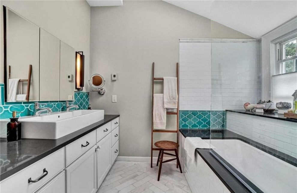 This is an example of a mid-sized transitional master bathroom in New York with shaker cabinets, white cabinets, an undermount tub, a shower/bathtub combo, multi-coloured tile, ceramic tile, marble floors, a vessel sink, engineered quartz benchtops, grey floor, a hinged shower door, brown benchtops, a shower seat, a double vanity, a built-in vanity and vaulted.