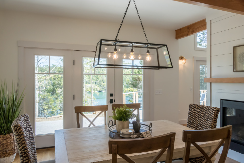 Medium sized beach style kitchen/dining room in Portland Maine with medium hardwood flooring, a two-sided fireplace, a timber clad chimney breast and exposed beams.