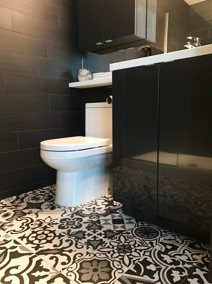 Small modern 3/4 bathroom in Chicago with flat-panel cabinets, black cabinets, a one-piece toilet, black and white tile, cement tile, black walls, cement tiles and an integrated sink.