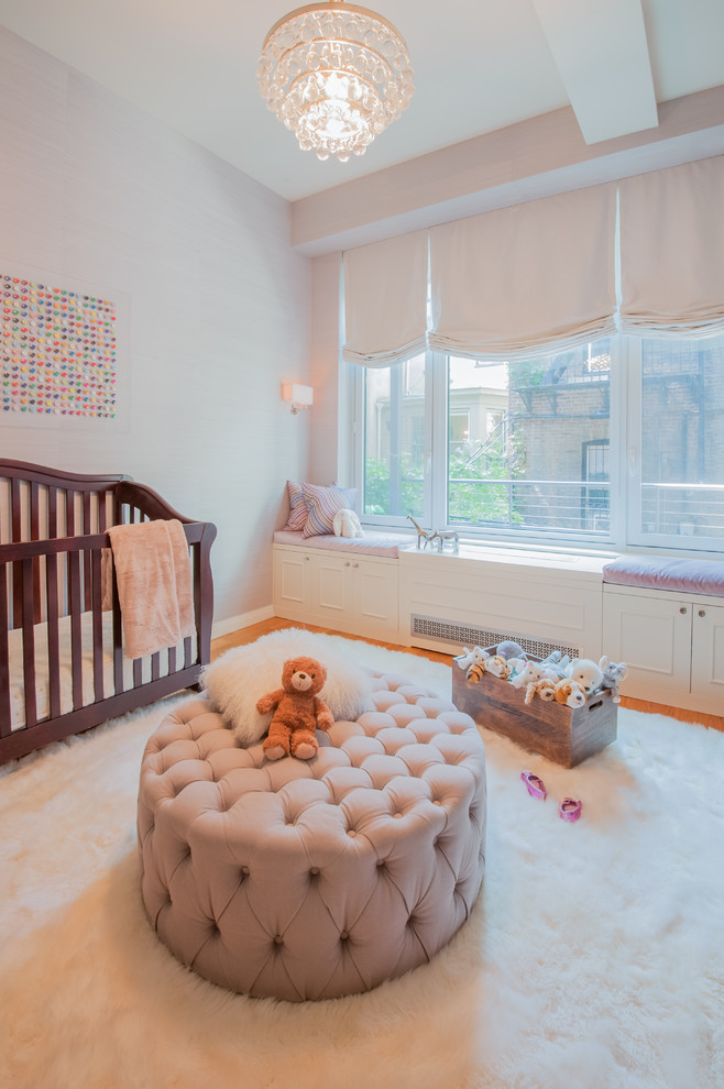 Photo of a mid-sized transitional nursery for girls in New York with purple walls and medium hardwood floors.