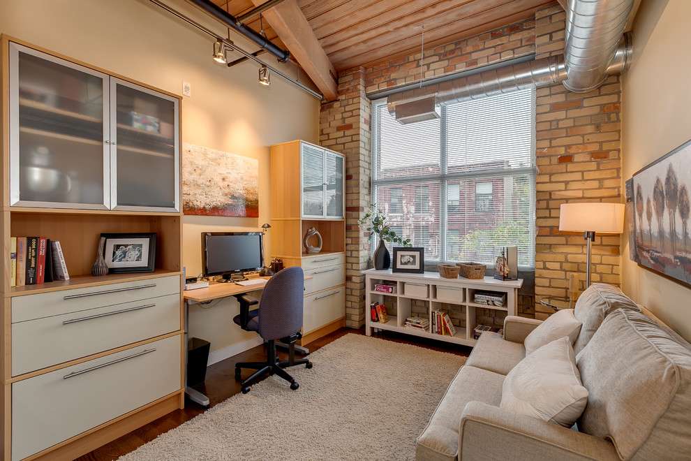 Inspiration for an industrial home office in Toronto with beige walls, dark hardwood floors and a built-in desk.