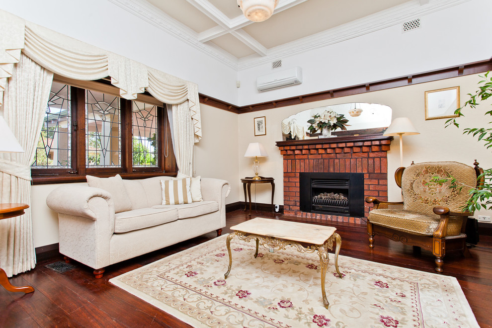 This is an example of a contemporary living room in Perth with beige walls, dark hardwood floors, a standard fireplace and a brick fireplace surround.