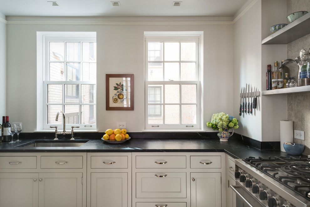 Design ideas for a traditional l-shaped kitchen in New York with an undermount sink, beige cabinets, soapstone benchtops, black benchtop, recessed-panel cabinets, grey splashback and stainless steel appliances.
