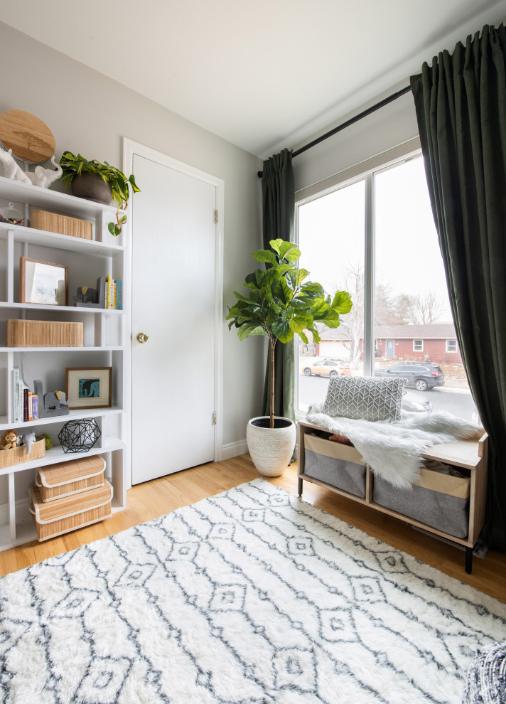 Design ideas for a small eclectic gender-neutral nursery in Denver with beige walls, light hardwood floors and wallpaper.
