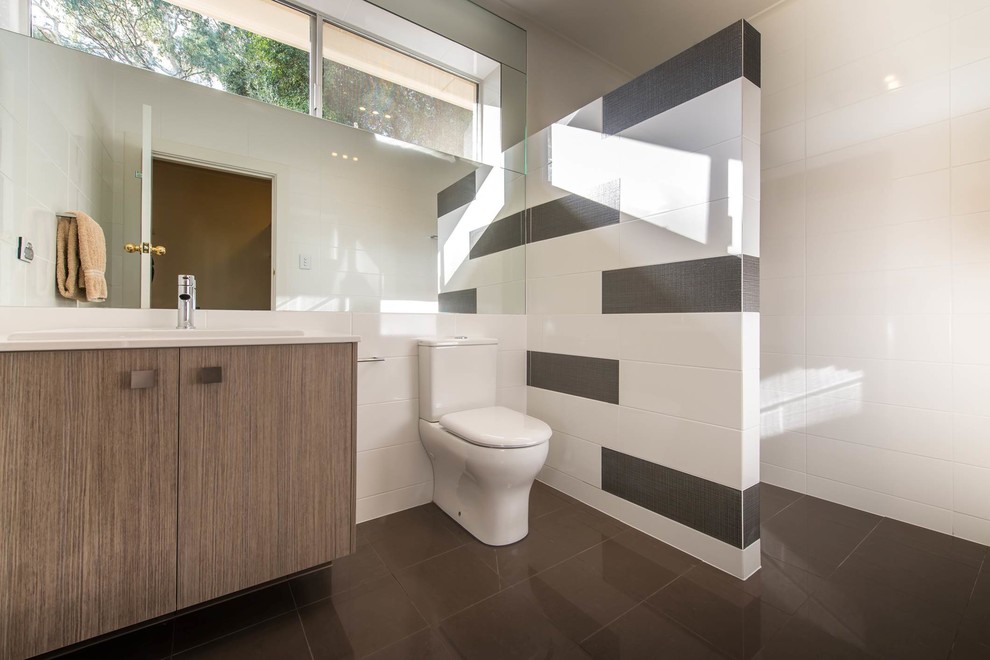 Inspiration for a mid-sized contemporary bathroom in Adelaide with flat-panel cabinets, medium wood cabinets, engineered quartz benchtops, an alcove shower, brown tile, porcelain tile, white walls, porcelain floors, a drop-in sink and a two-piece toilet.