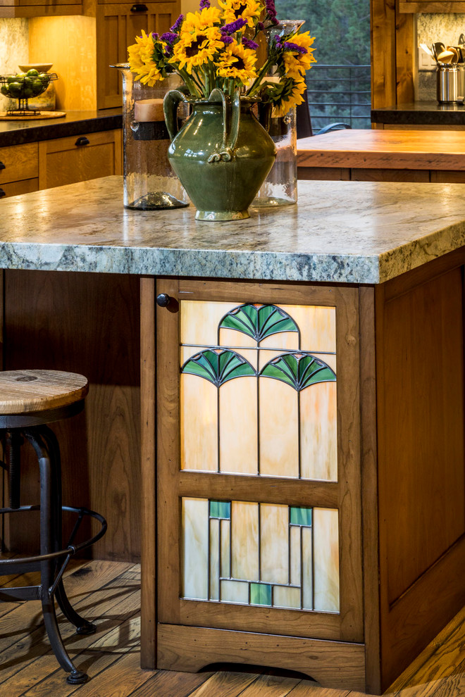 Enclosed kitchen - large rustic u-shaped medium tone wood floor and brown floor enclosed kitchen idea with a farmhouse sink, shaker cabinets, medium tone wood cabinets, soapstone countertops, multicolored backsplash, stone slab backsplash, paneled appliances, two islands and black countertops