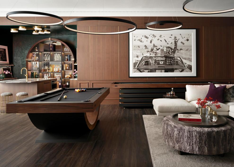 Large transitional walk-out dark wood floor, brown floor and wood wall basement photo in Denver with brown walls, a corner fireplace and a stone fireplace