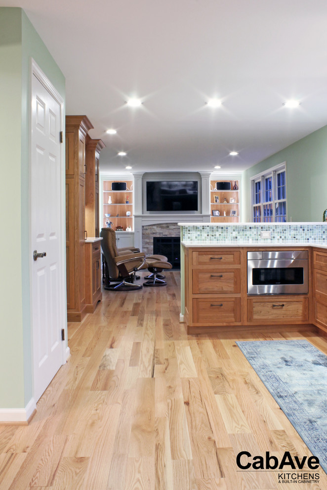 Large transitional u-shaped light wood floor and beige floor open concept kitchen photo with an undermount sink, recessed-panel cabinets, light wood cabinets, quartz countertops, green backsplash, mosaic tile backsplash, stainless steel appliances and a peninsula