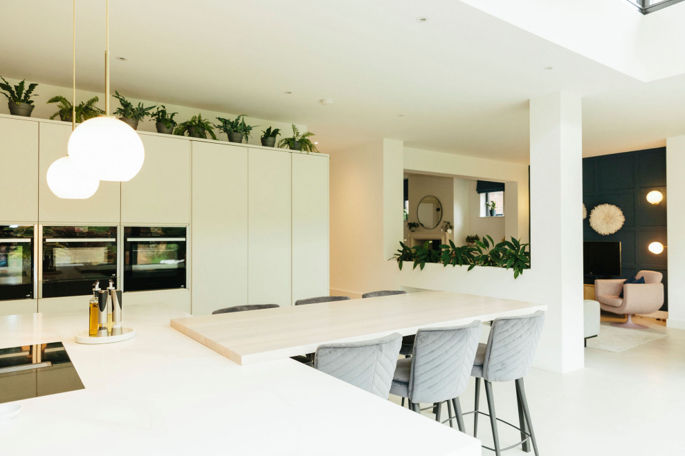 Design ideas for an expansive l-shaped eat-in kitchen in Hampshire with a drop-in sink, flat-panel cabinets, blue cabinets, marble benchtops, beige splashback, brick splashback, concrete floors, multiple islands, grey floor and white benchtop.