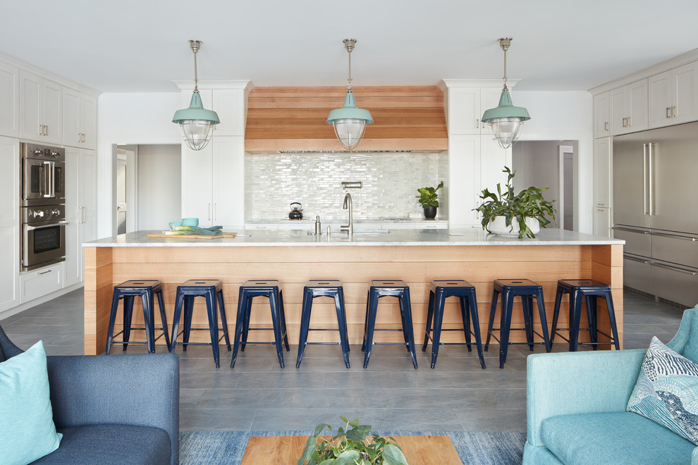 Beach style gray floor open concept kitchen photo in Manchester with shaker cabinets, white cabinets, white backsplash, stainless steel appliances, an island and white countertops