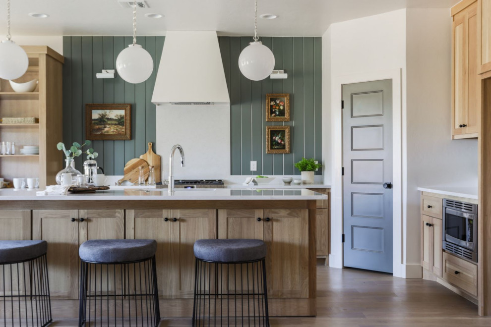Inspiration for a mid-sized transitional l-shaped open plan kitchen in Oklahoma City with an undermount sink, shaker cabinets, light wood cabinets, quartz benchtops, white splashback, engineered quartz splashback, stainless steel appliances, light hardwood floors, with island, beige floor and white benchtop.