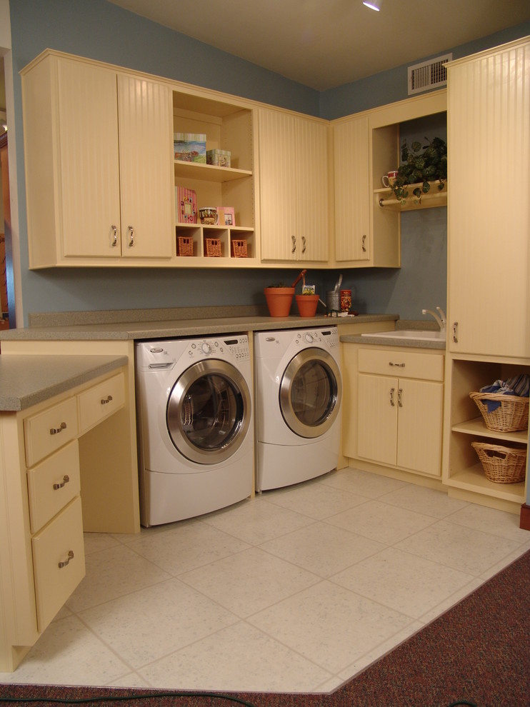 Design ideas for a mid-sized country l-shaped utility room in Other with a drop-in sink, flat-panel cabinets, yellow cabinets, laminate benchtops and a side-by-side washer and dryer.