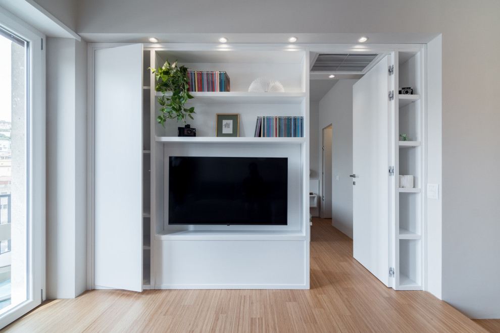 Imagen de salón abierto actual pequeño con paredes grises, suelo de bambú y pared multimedia