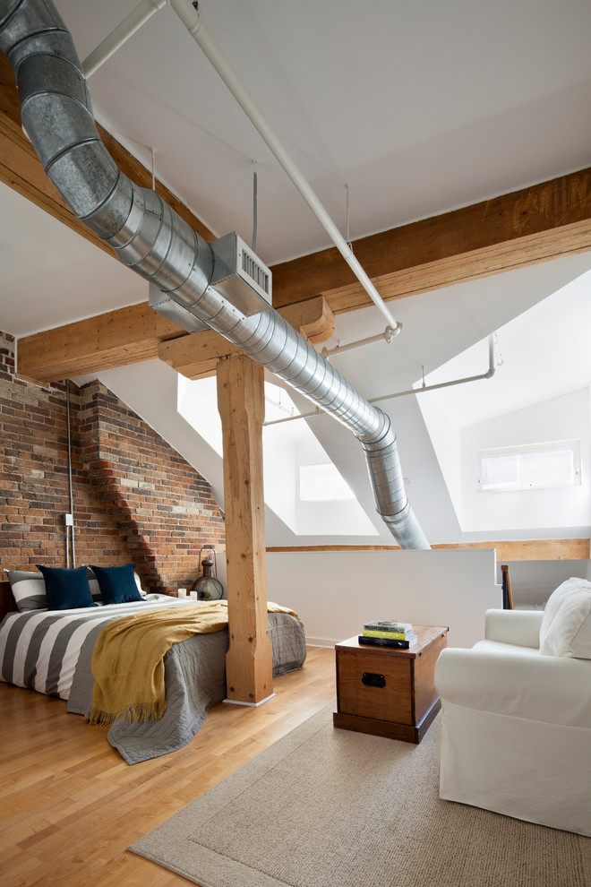 Inspiration for a large industrial loft-style bedroom in Toronto with white walls and light hardwood floors.