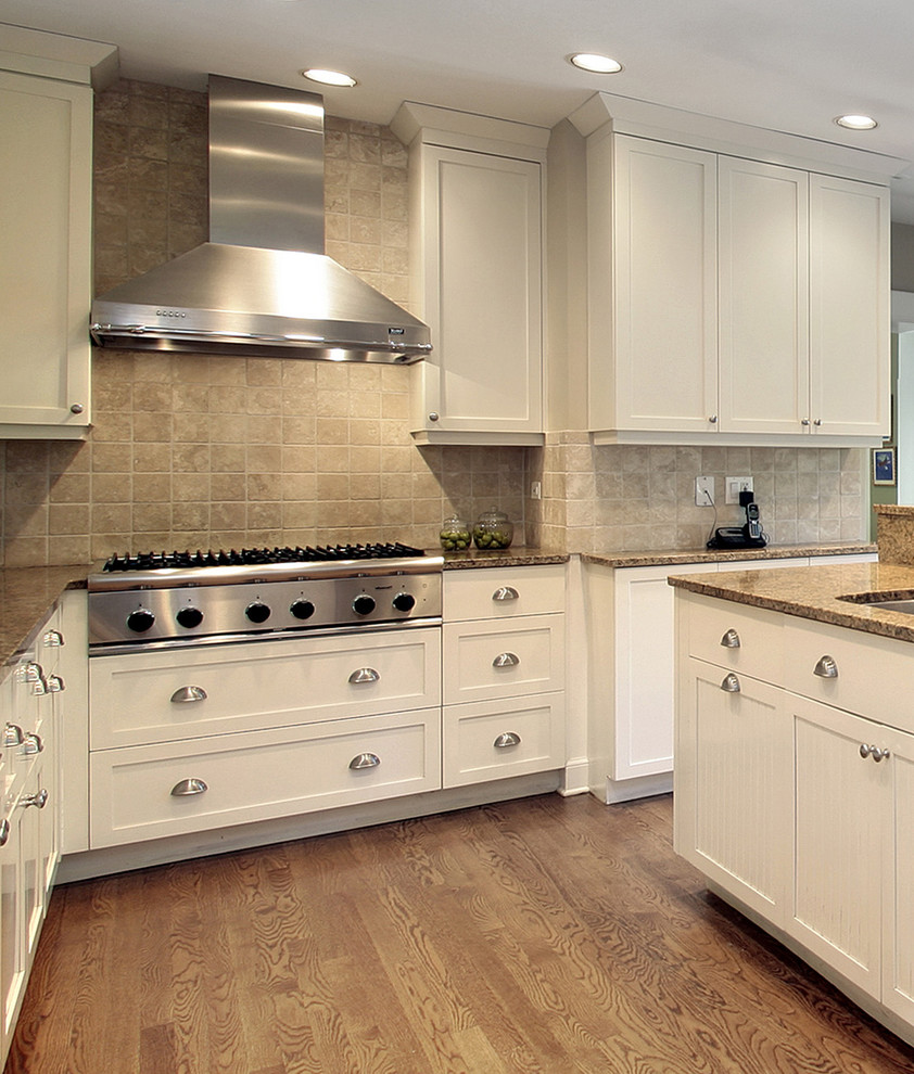 Inspiration for a mid-sized transitional l-shaped medium tone wood floor eat-in kitchen remodel in Toronto with an undermount sink, flat-panel cabinets, white cabinets, quartz countertops, beige backsplash, stone tile backsplash, stainless steel appliances and an island