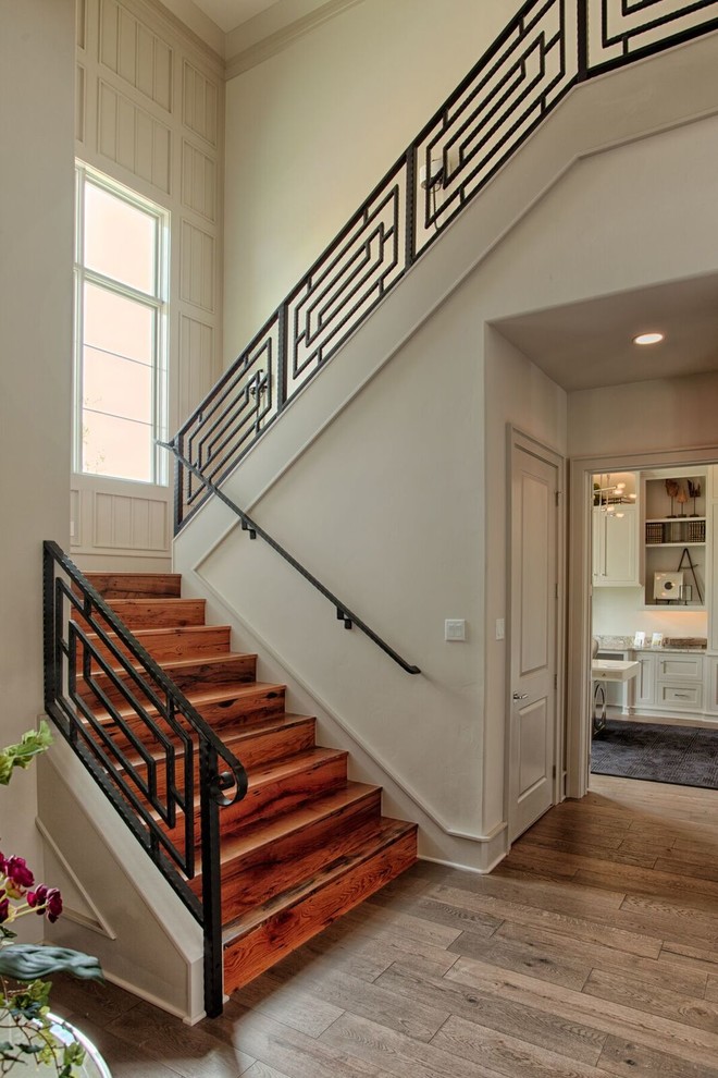 Design ideas for a large transitional wood u-shaped staircase in Austin with wood risers and metal railing.