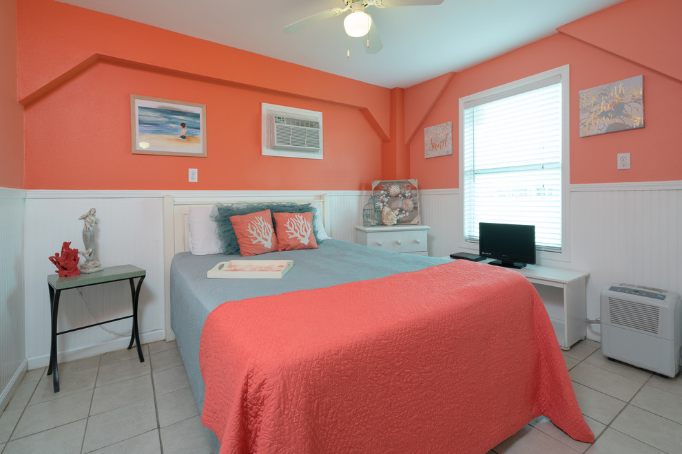 This is an example of a small beach style guest bedroom in Houston with ceramic floors, beige floor and orange walls.