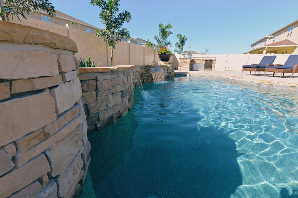 This is an example of a mid-sized tropical backyard custom-shaped pool in Orlando with brick pavers.