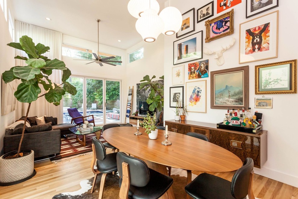 Photo of a mid-sized eclectic open plan dining in Austin with white walls, light hardwood floors, no fireplace and brown floor.