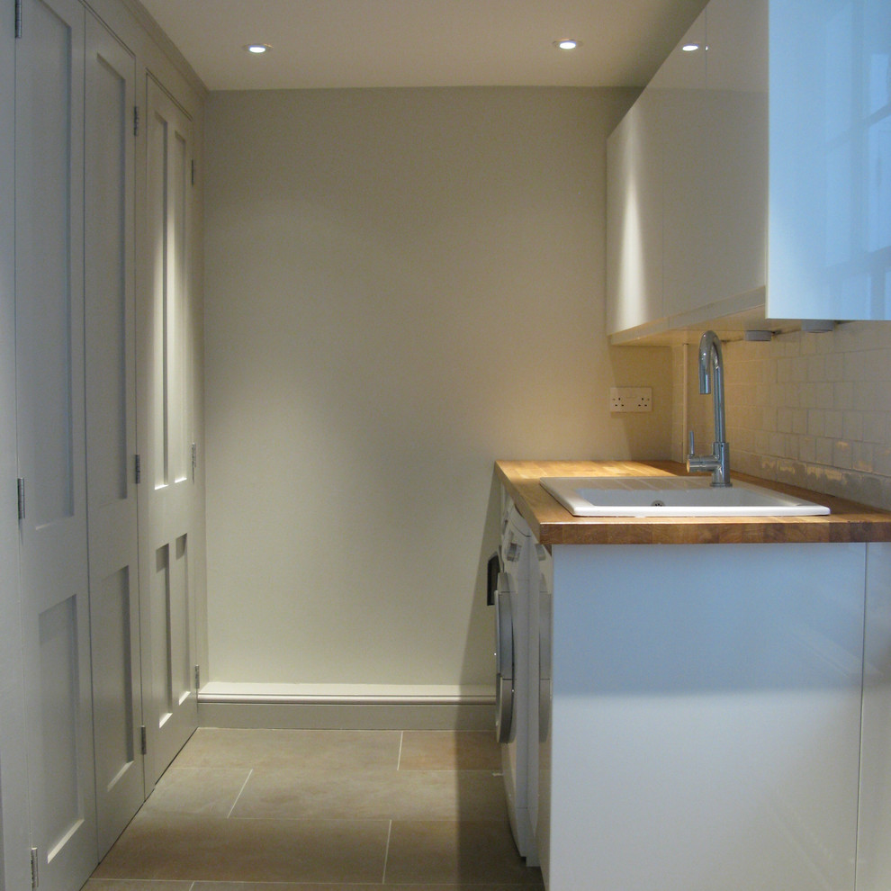This is an example of a small traditional galley utility room in Sussex with recessed-panel cabinets, grey cabinets and wood benchtops.