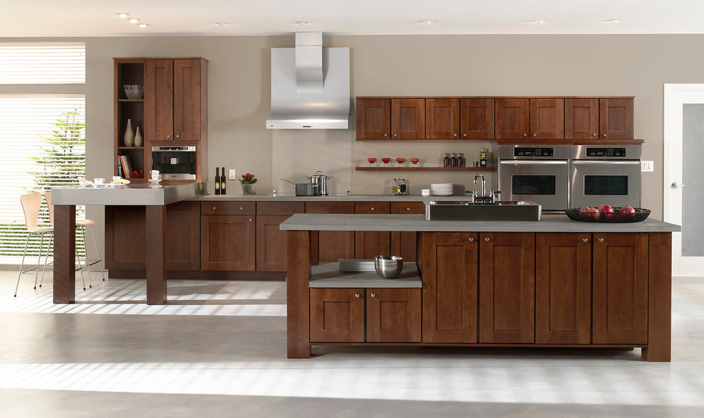 Photo of a large traditional single-wall eat-in kitchen in Other with dark wood cabinets, stainless steel appliances, a drop-in sink, shaker cabinets, concrete benchtops, concrete floors and multiple islands.