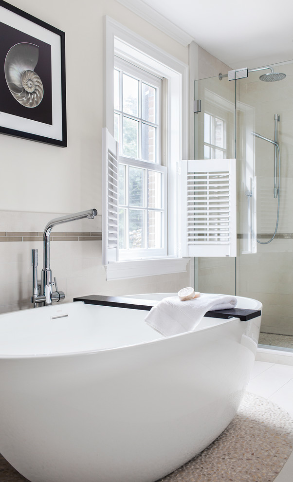 Freestanding bathtub - transitional pebble tile floor freestanding bathtub idea in Boston with beige walls