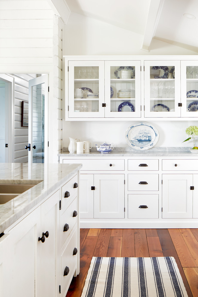 Inspiration for a mid-sized beach style l-shaped open plan kitchen in Toronto with an undermount sink, shaker cabinets, white cabinets, marble benchtops, grey splashback, stone tile splashback, stainless steel appliances, medium hardwood floors, with island, brown floor and grey benchtop.