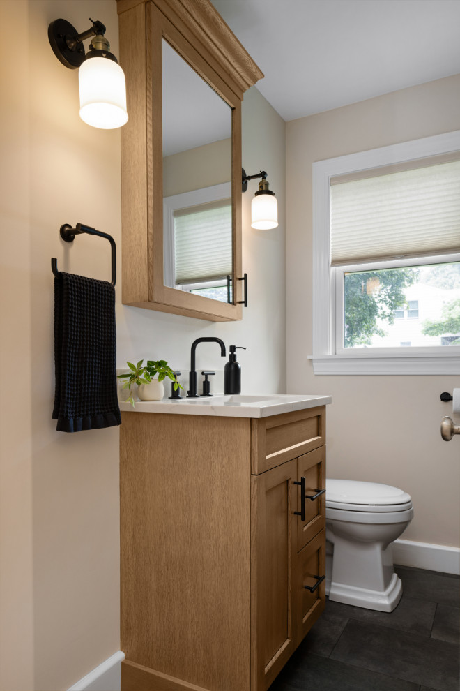 This is an example of a transitional bathroom in Boston with shaker cabinets, brown cabinets, an alcove tub, an alcove shower, a two-piece toilet, beige tile, porcelain tile, beige walls, porcelain floors, an undermount sink, engineered quartz benchtops, grey floor, a sliding shower screen, beige benchtops, a single vanity and a built-in vanity.