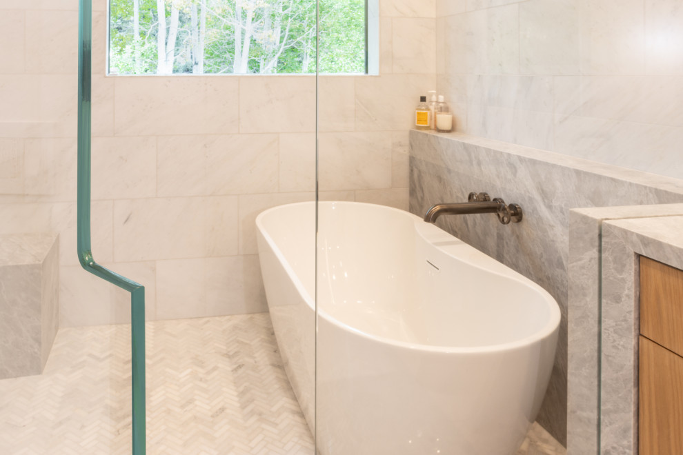 Exemple d'une grande salle de bain principale scandinave en bois clair avec un placard à porte plane, une baignoire indépendante, un combiné douche/baignoire, un carrelage blanc, du carrelage en marbre, un mur blanc, un sol en marbre, un plan de toilette en marbre, un sol blanc, une cabine de douche à porte battante, un plan de toilette gris, un banc de douche et meuble-lavabo encastré.
