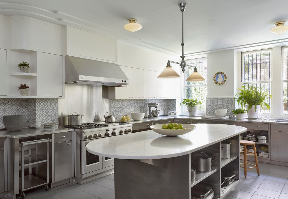 This is an example of a large traditional u-shaped enclosed kitchen in New York with an integrated sink, flat-panel cabinets, white cabinets, stainless steel worktops, multi-coloured splashback, cement tile splashback, stainless steel appliances, porcelain flooring, an island, grey floors and grey worktops.