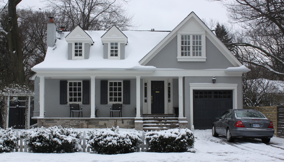 Photo of a mid-sized traditional two-storey stucco grey house exterior in Toronto with a gable roof.