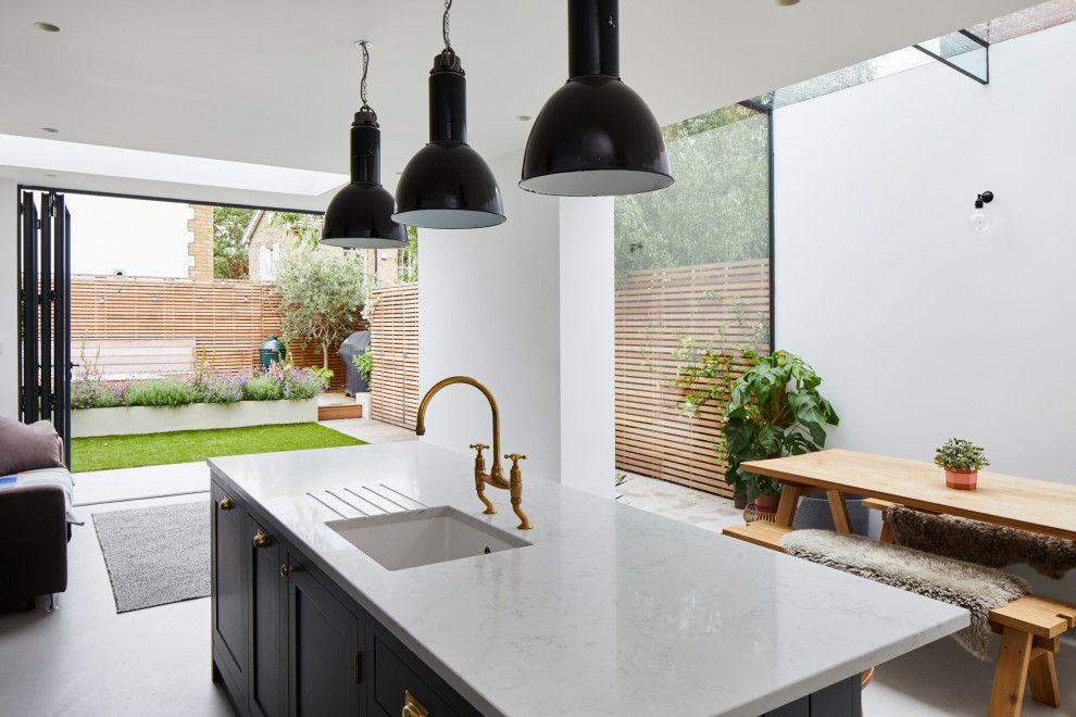 Design ideas for a mid-sized contemporary eat-in kitchen in London with an undermount sink, shaker cabinets, black cabinets, with island, white floor and white benchtop.