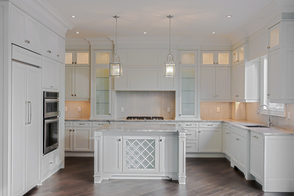 Design ideas for a large transitional u-shaped eat-in kitchen in Toronto with an undermount sink, shaker cabinets, white cabinets, marble benchtops, beige splashback, stainless steel appliances, medium hardwood floors, with island and brown floor.