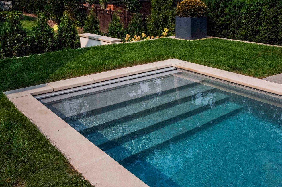 Design ideas for a mid-sized traditional backyard rectangular lap pool in Chicago with a hot tub and natural stone pavers.