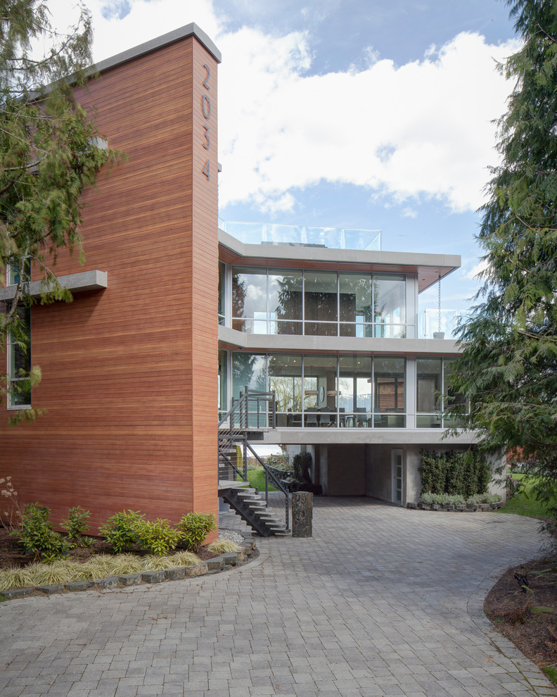This is an example of a contemporary three-storey glass exterior in Vancouver with a flat roof.