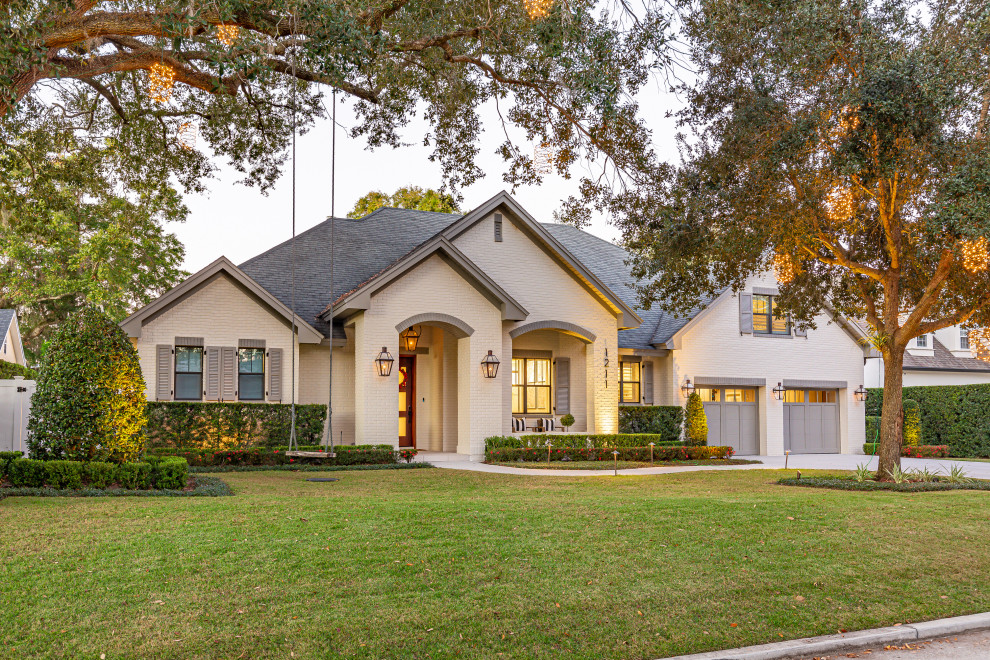 Large transitional white one-story brick exterior home photo in Orlando with a shingle roof and a gray roof