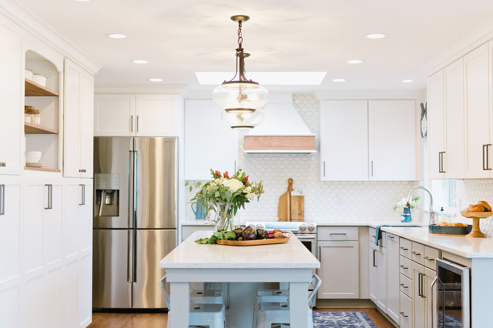Open concept kitchen - mid-sized transitional u-shaped medium tone wood floor and brown floor open concept kitchen idea with an undermount sink, shaker cabinets, white cabinets, quartz countertops, white backsplash, porcelain backsplash, stainless steel appliances, an island and white countertops